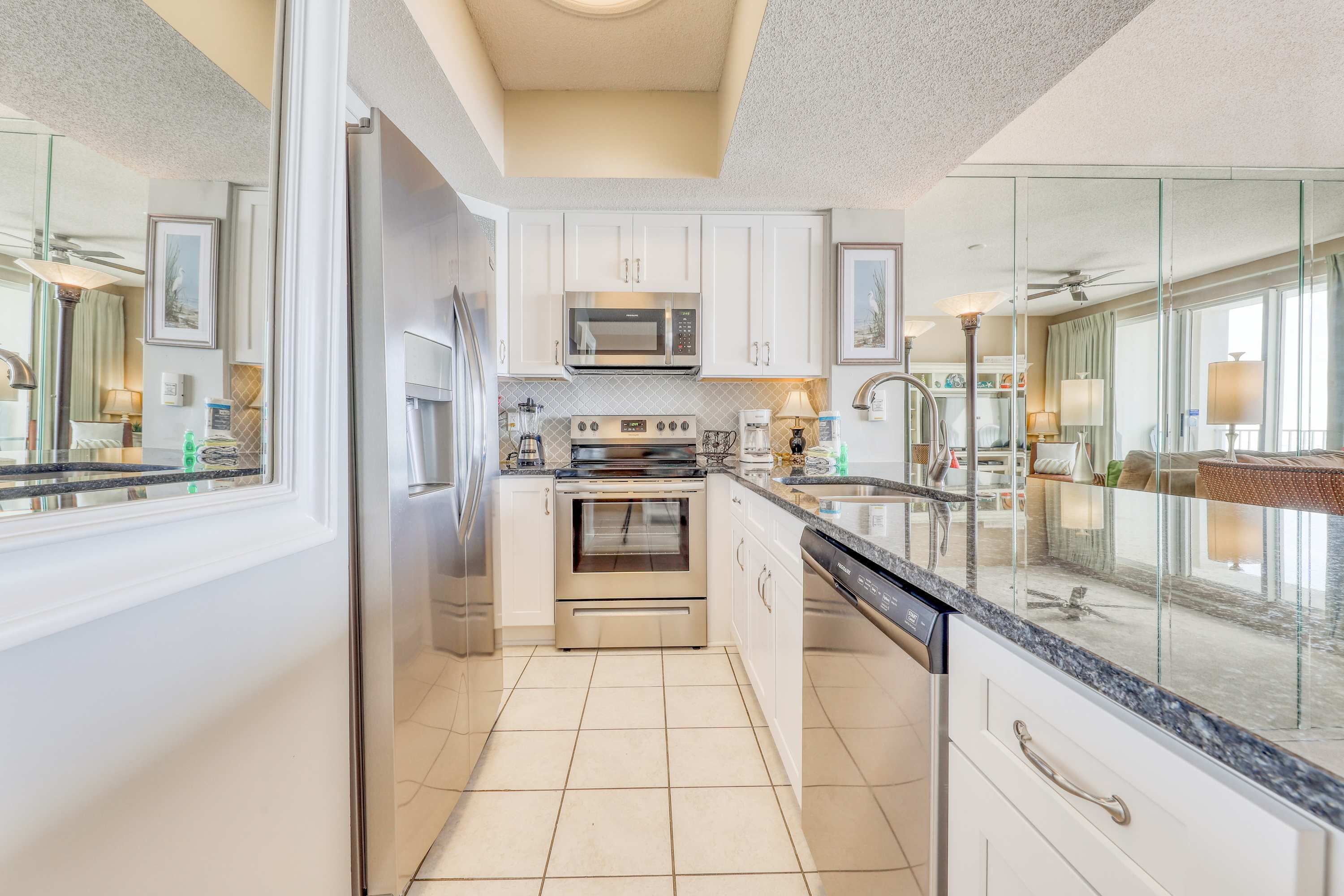 A modern kitchen with white cabinets, stainless steel appliances, and a large window.