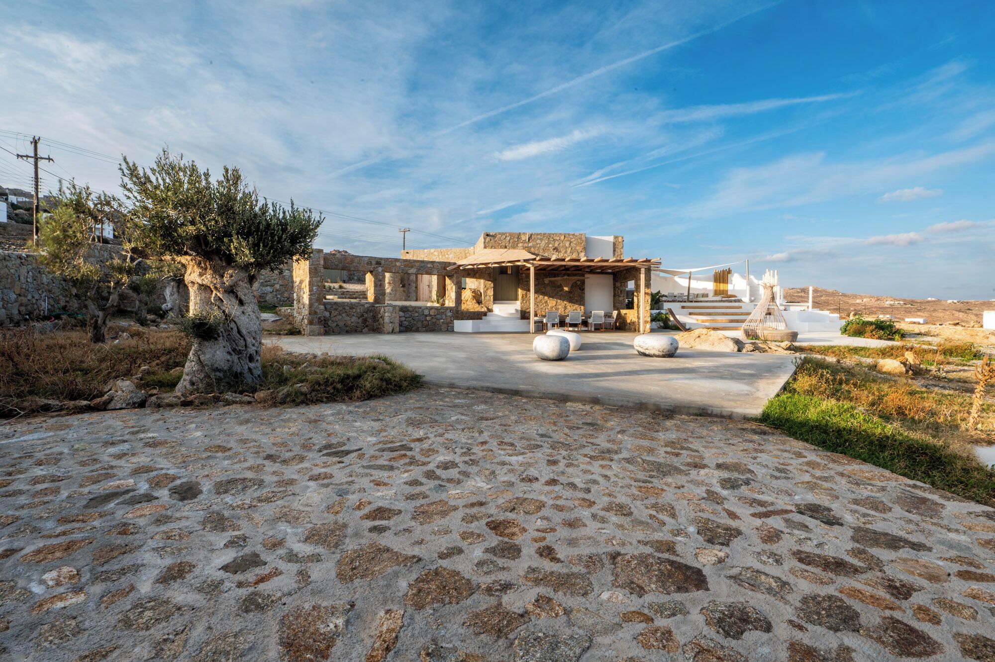 A stone-paved courtyard with a stone building featuring a pergola and outdoor seating.