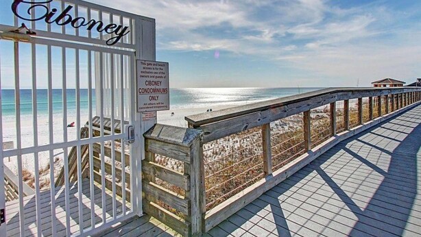 Ein Holzsteg führt zu einem befestigten Bereich mit einem Schild, auf dem 'Ciboney Condominiums Only' steht.