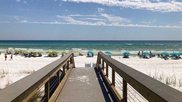 A wooden boardwalk leading to a beach with turquoise umbrellas and lounge chairs. - Gorgeous coastal home with shared pools, golf cart, and beach access (Miramar Beach)