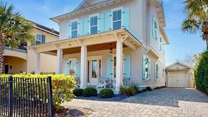A two-story house with a covered porch, a garage, and a well-maintained front yard. - Gorgeous coastal home with shared pools, golf cart, and beach access (Miramar Beach)