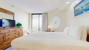A hotel room with a large bed, a wooden dresser, a television, and a view of the outdoors. - Resort condo with pool, hot tub & on-site dining, near the beach (Miramar Beach)