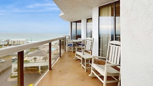 A balcony with a view of the ocean, white chairs, and a table. - Resort condo with pool, hot tub & on-site dining, near the beach (Miramar Beach)