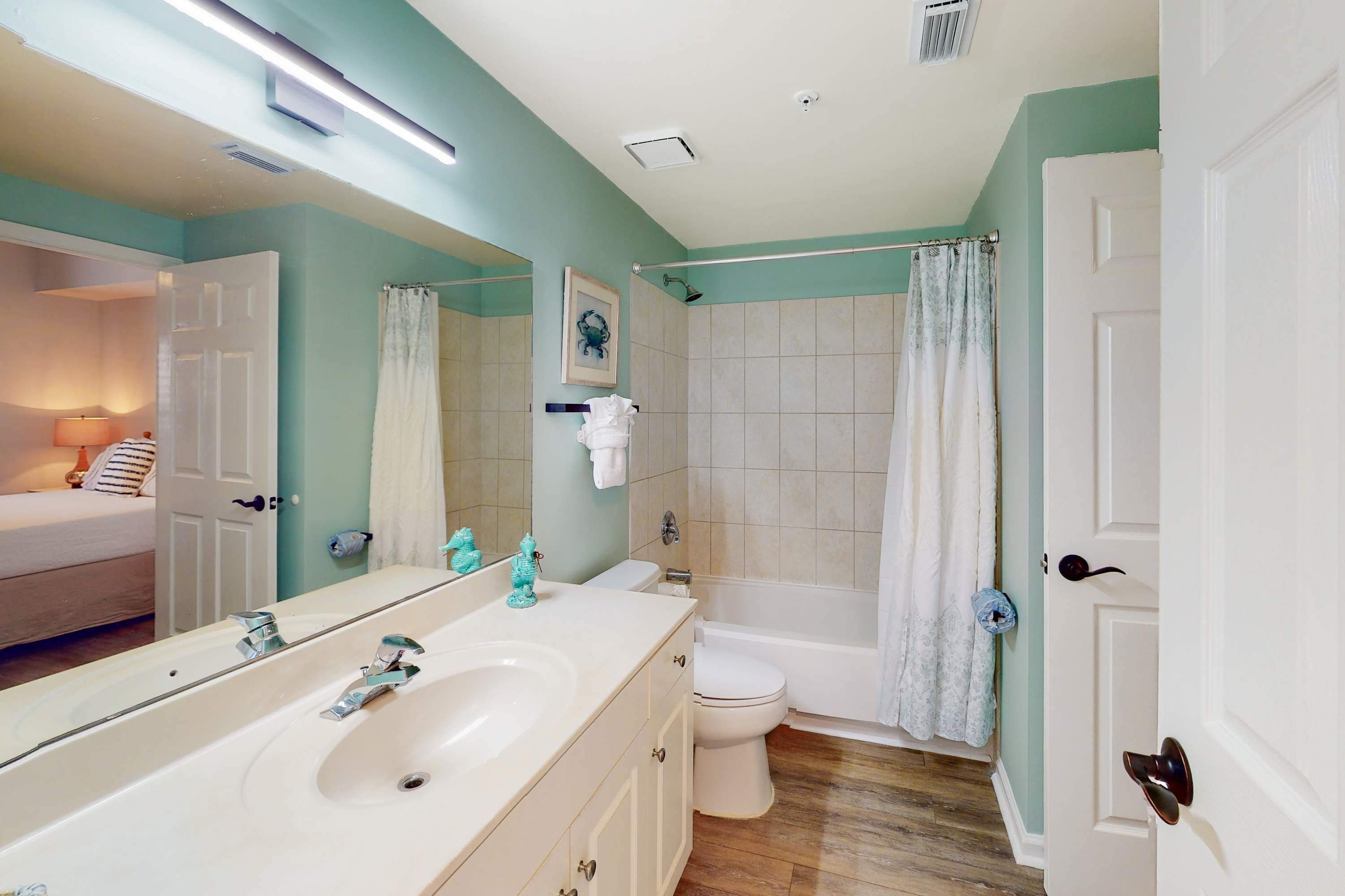 A bathroom with a large mirror, a sink, a toilet, and a shower.