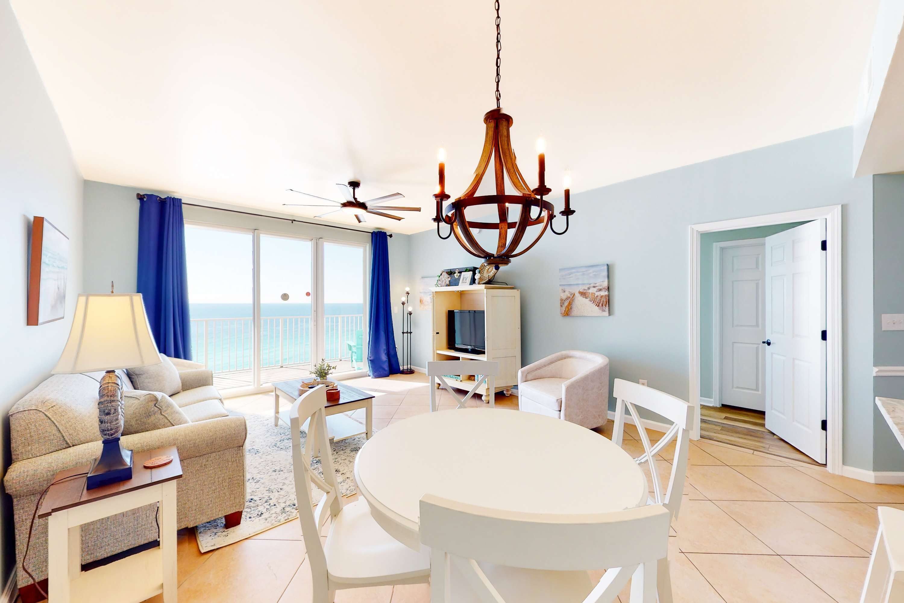 A spacious living room with a white dining table, a sofa, and a TV stand.