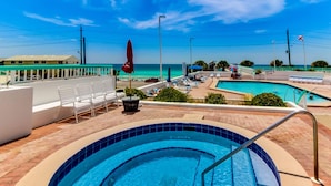 Ein Pool mit Blick auf den Ozean, Liegestühle und Sonnenschirme.