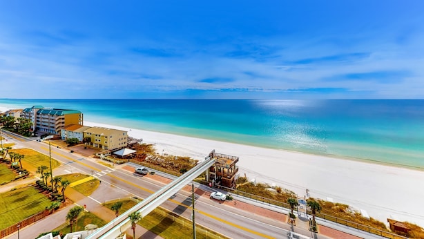 Eine Küstenstraße mit Fußgängerbrücke, Strand und Gebäuden.