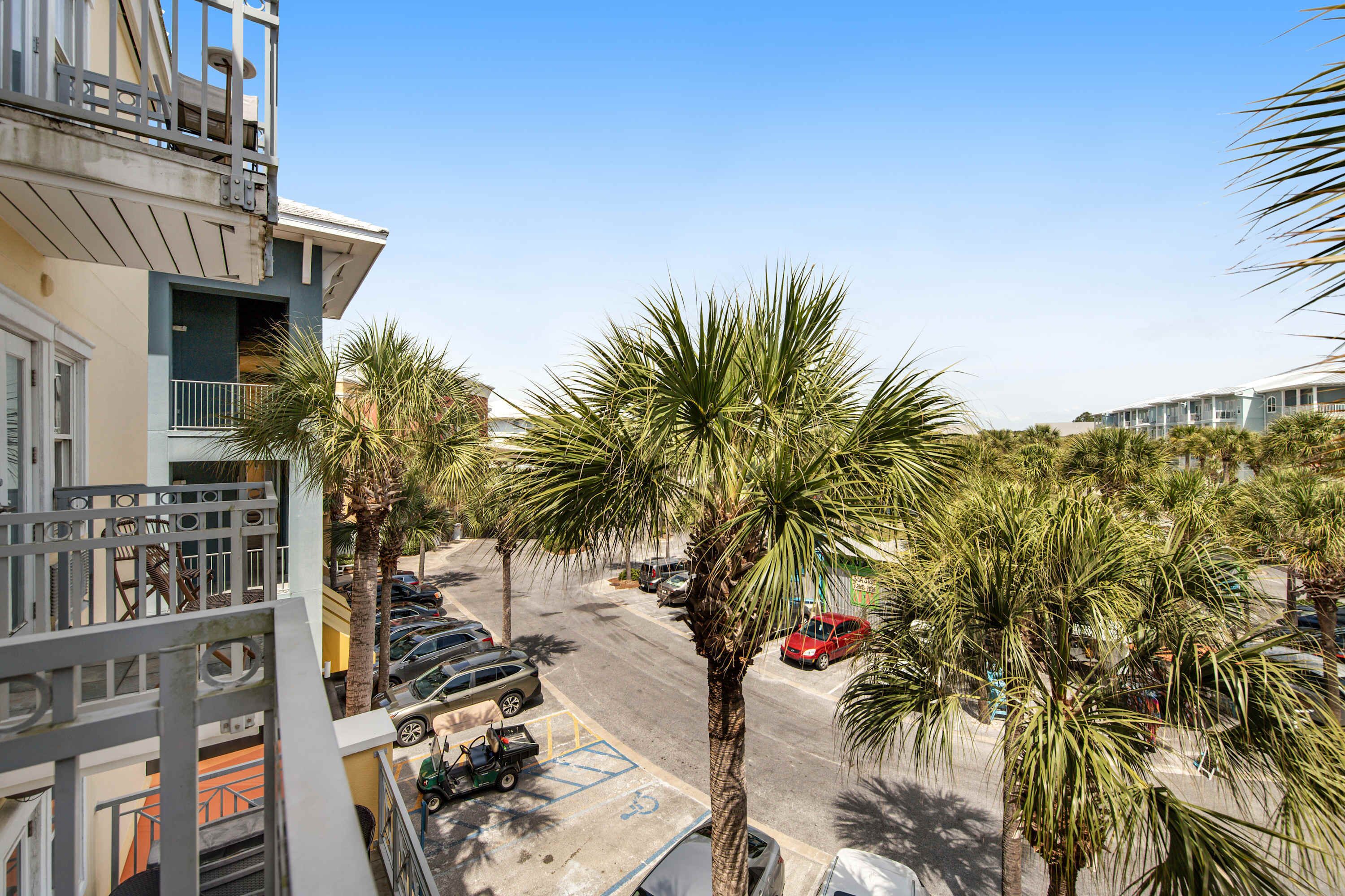 A residential area with a street, parked cars, and palm trees.