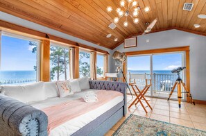 A bedroom with a large bed, a view of the sea, a balcony with a telescope, and a wooden ceiling. - Gulf-front, dog-friendly home with private pool, great view, deck & beach access (Carrabelle)