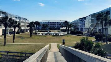 A modern hotel with a central courtyard, surrounded by palm trees and a wooden boardwalk.