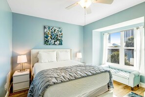 A bedroom with a bed, bedside lamps, a ceiling fan, a window with curtains, and a painting on the wall. - Two-story townhome near the beach with WiFi, 3 balconies & HEATED pool (Navarre Beach)