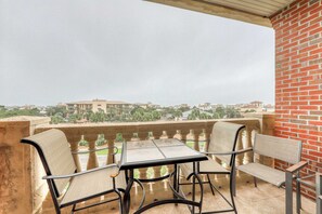 Ein Balkon mit Tisch und Stühlen, eine Backsteinmauer und Blick auf Gebäude und Grünflächen.