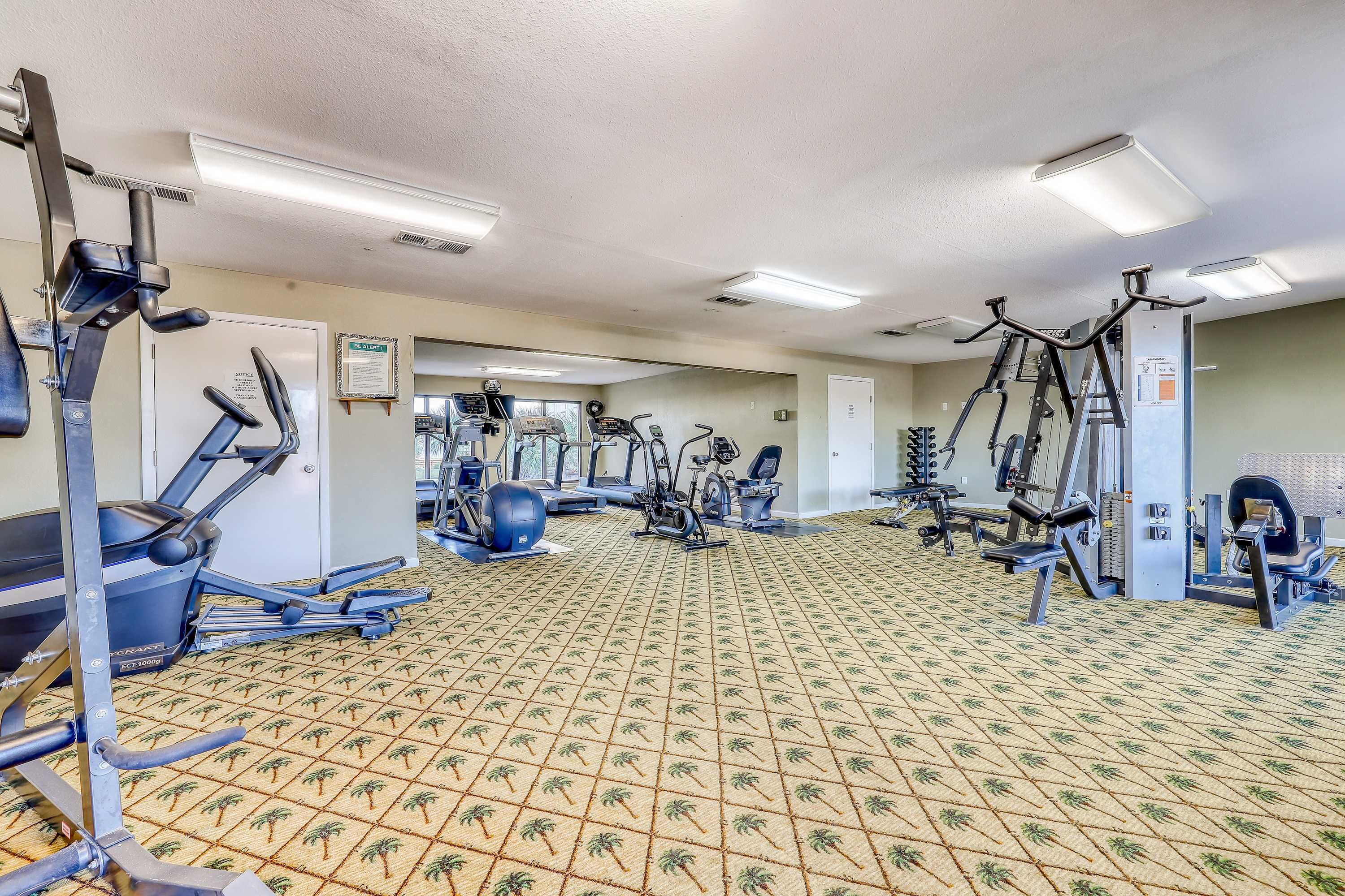 Une salle de sport équipée de divers appareils d’exercice, notamment des tapis de course, des vélos d’appartement et des appareils de musculation.