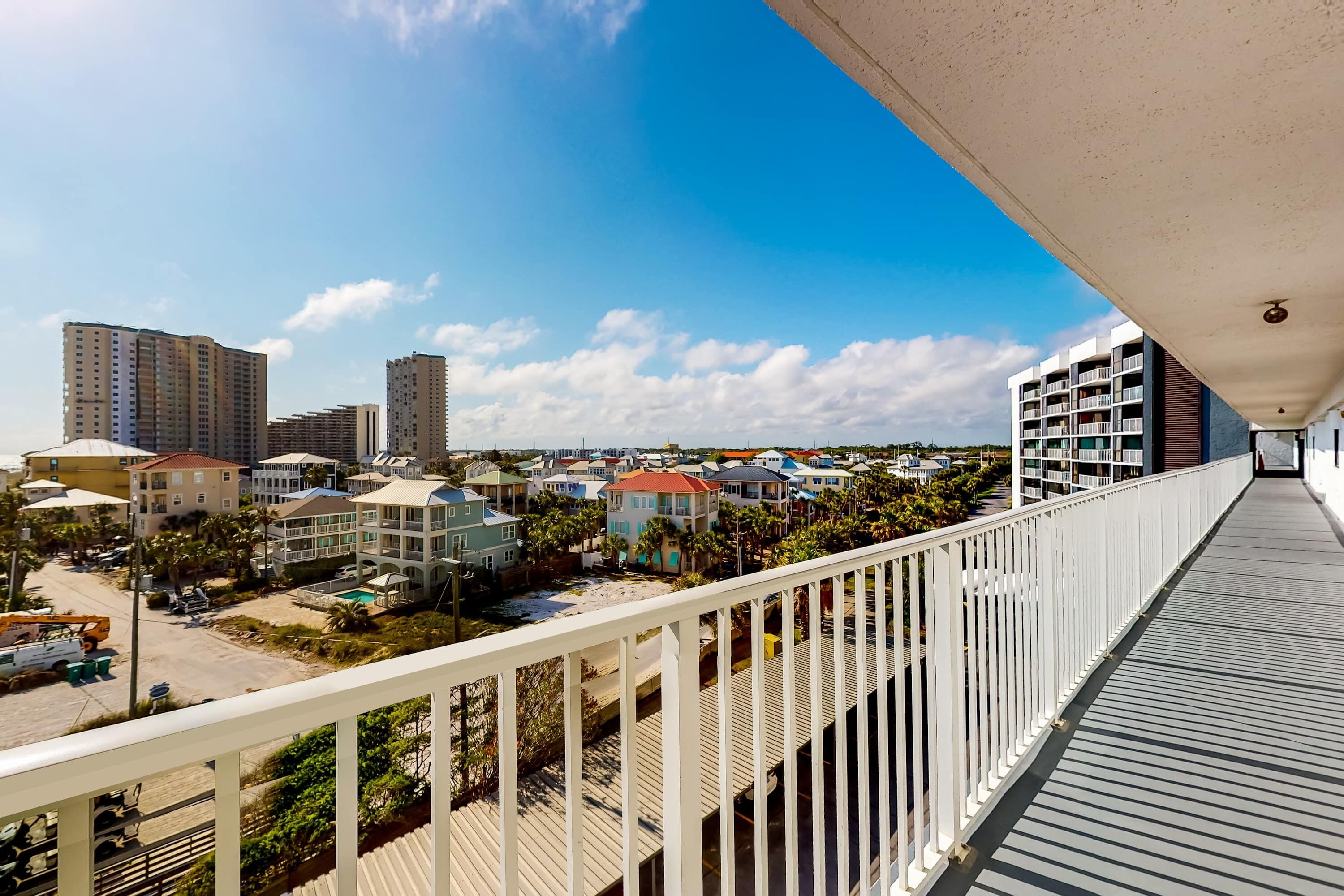 A balcony with a view of a residential area, including houses and a distant building.