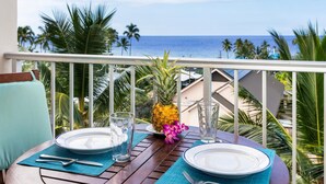 A table set for two with plates, cutlery, a glass, and a pineapple on a balcony overlooking the ocean. - Kailua Village#604 High Floor, Gorgeous Remodeled 1 bedroom, in Heart of Town (Kailua Kona)