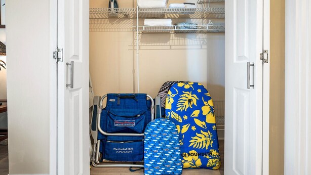 A walk-in closet with shelves for hanging clothes, a suitcase, and a patterned bath mat. - Kailua Village#604 High Floor, Gorgeous Remodeled 1 bedroom, in Heart of Town (Kailua Kona)