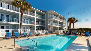 Un hôtel doté d’une piscine, de plusieurs balcons et de chaises bleues.