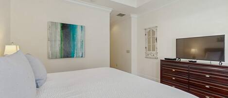 Un dormitorio con una cama grande, un aparador, un televisor y un cuadro en la pared.
