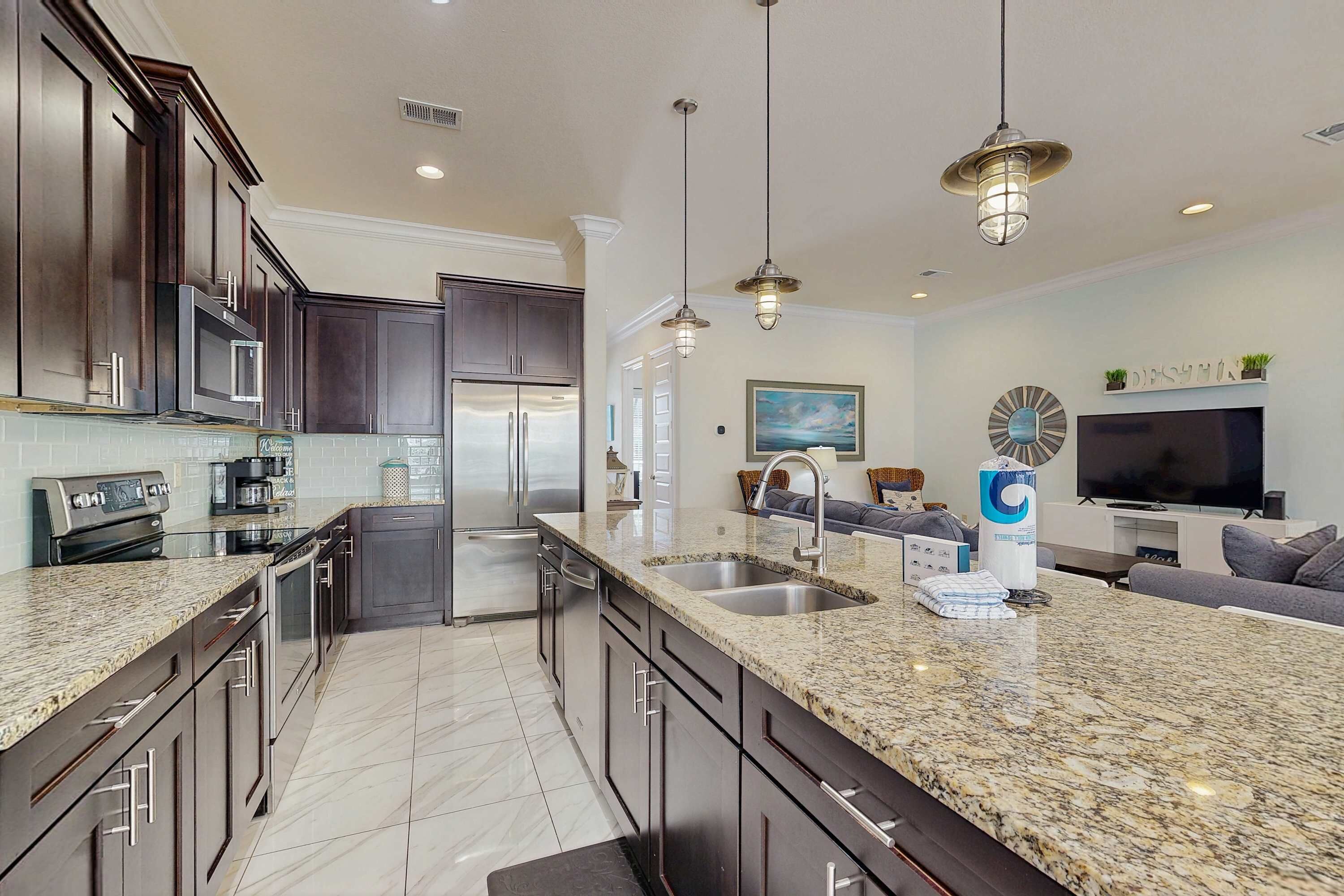 A modern kitchen with dark wood cabinets, granite countertops, stainless steel appliances, and pendant lighting.