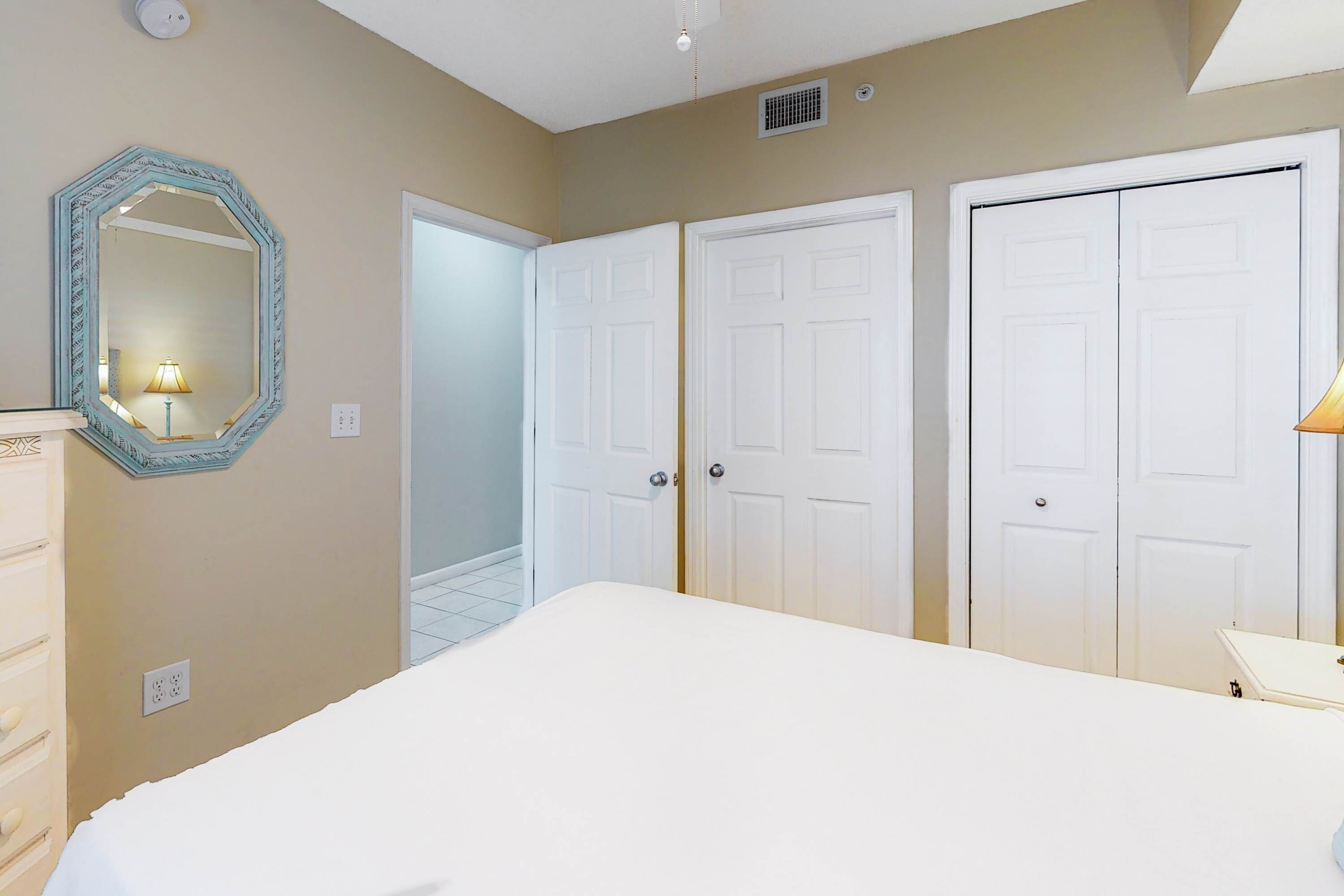 A bedroom with a bed, a dresser, a mirror, and two wardrobes.