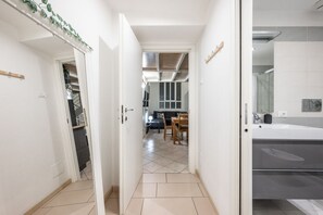 A narrow hallway leading to a dining area with a tiled floor and a kitchen with a white sink and cabinets. - Verdi's Nest - Loft with Wifi and A/C (Milano)
