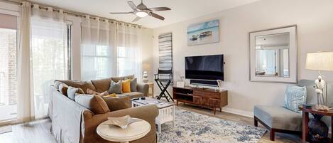 A living room with a sofa, TV, and a ceiling fan.