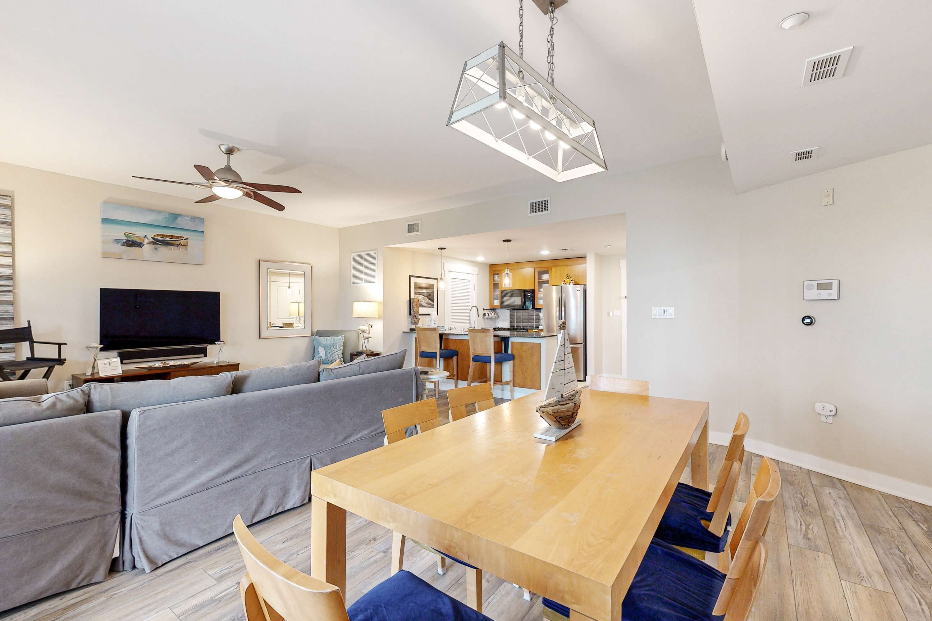 A modern living room with a sofa, TV, and dining area with a wooden table and chairs.