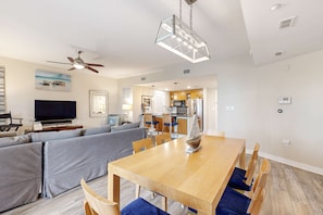 Ein modernes Wohnzimmer mit Sofa, Fernseher und Essbereich mit Holztisch und Stühlen.