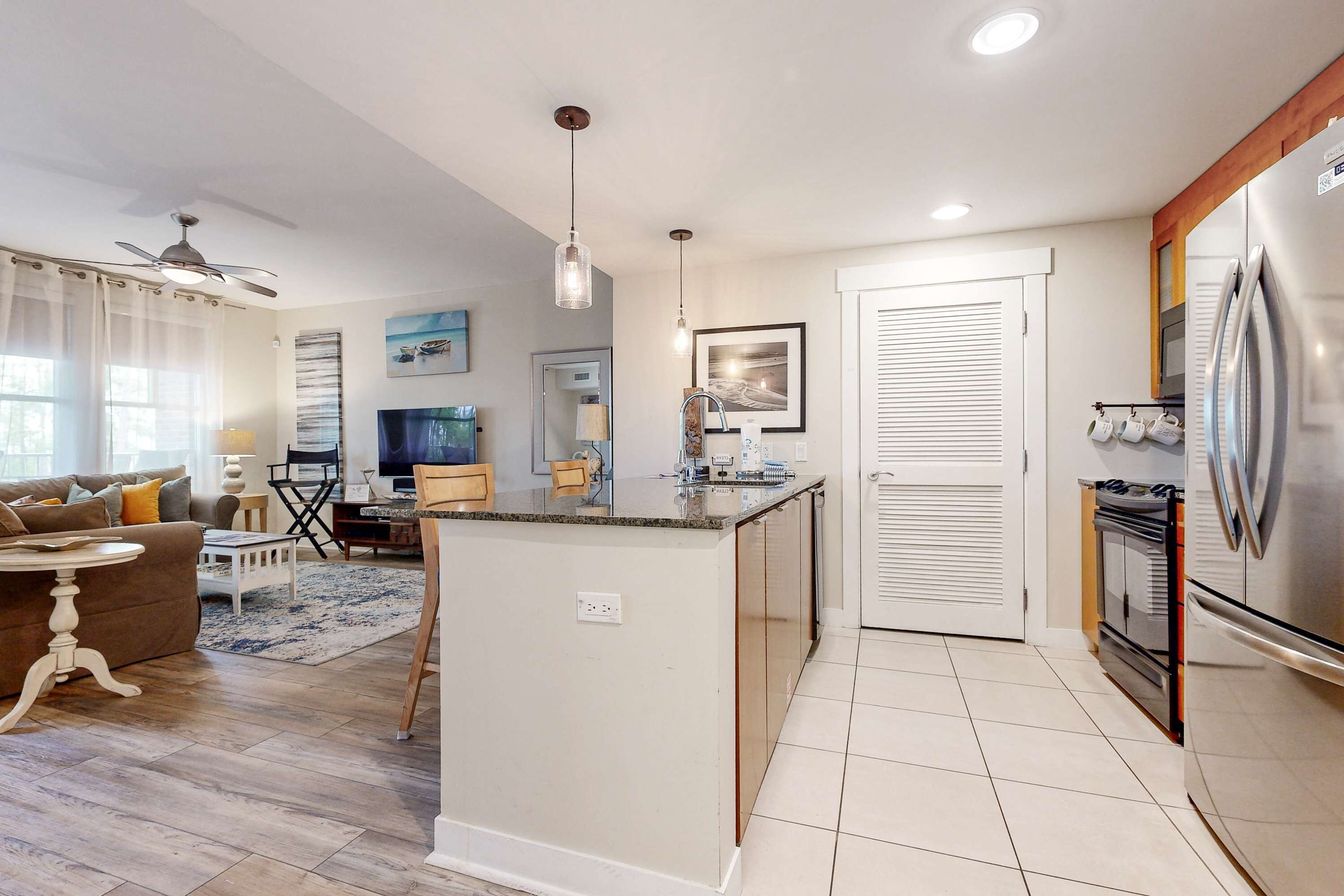 A modern kitchen with a central island, a dining area with a sofa and chairs, and a living room with a TV and a coffee table.