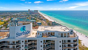 Ett högt hotell med en tydlig skylt som visar namnet ”Surfside”, flera balkonger och utsikt över stranden.