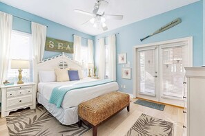 Ein Schlafzimmer mit Bett, Nachttisch, Sitzbank und Deckenventilator.