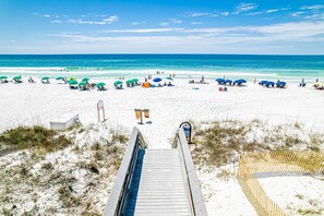 A beach with a wooden boardwalk leading to the shore, featuring umbrellas and beach chairs. - Charming home with wraparound balcony & central AC - 1/2 block to the beach (Miramar Beach)