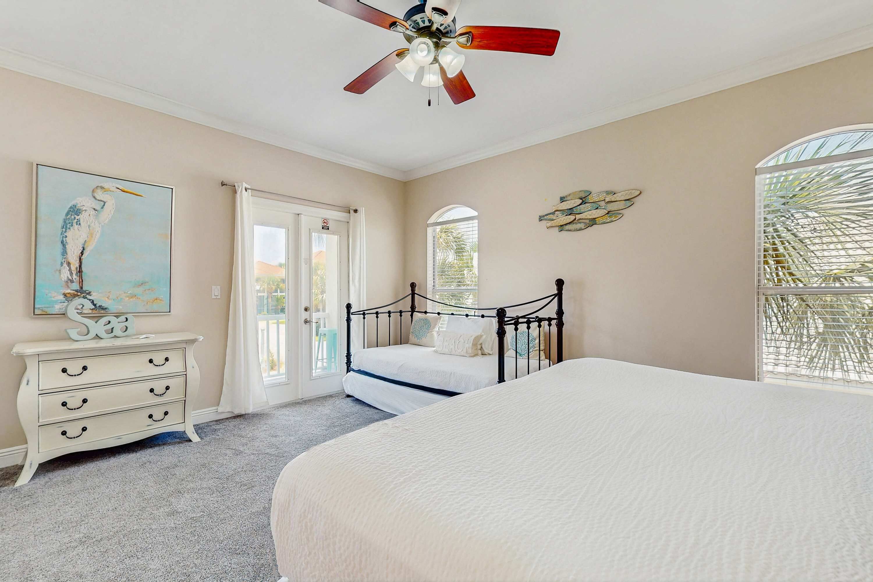 Quarto com cama, cômoda, ventilador de teto e um quadro.