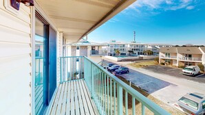 A balcony with a view of a parking lot and buildings in the background. - Beautifully updated 2nd-floor condo near the beach with pool, balcony, W/D, & AC (Miramar Beach)