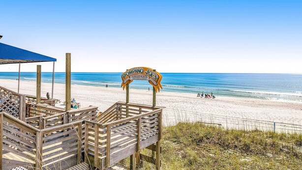 A wooden boardwalk leading to a beach with a sign for 'Pompano Joe's Seafood House'. - Beautifully updated 2nd-floor condo near the beach with pool, balcony, W/D, & AC (Miramar Beach)