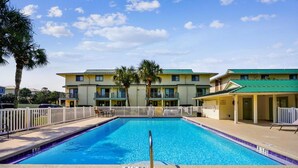 A rectangular swimming pool with a diving board in the center, surrounded by a white fence. - Beautifully updated 2nd-floor condo near the beach with pool, balcony, W/D, & AC (Miramar Beach)