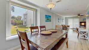 Un comedor amplio con una gran mesa de madera, varias sillas y vistas al jardín a través de amplios ventanales.