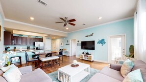 A spacious living area with a kitchen, dining area, and a TV wall. - Beach service included at gated coastal condo with pool, hot tub, W&D, & balcony (Miramar Beach)