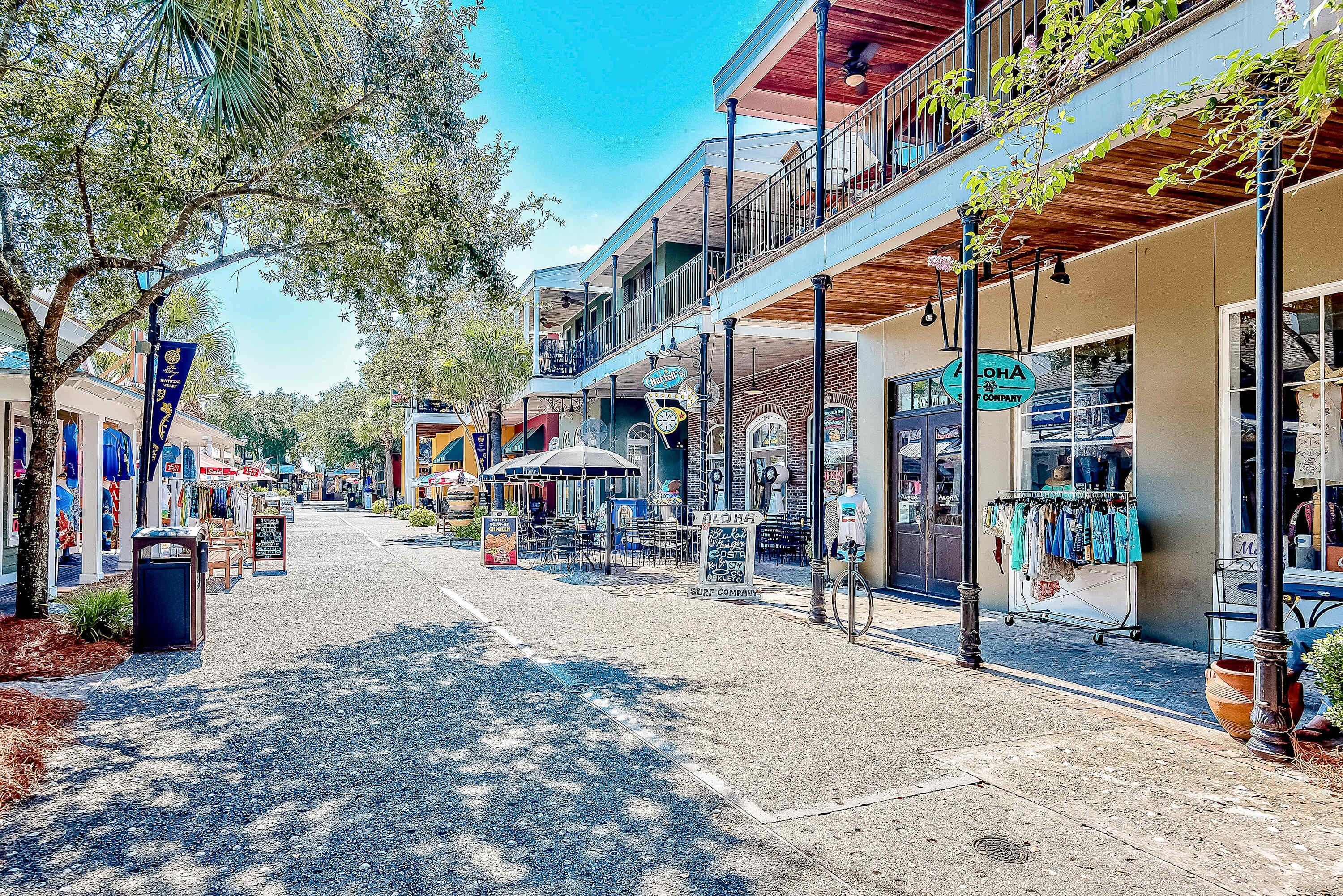 A street lined with shops and cafes, featuring outdoor seating and a clear sky.