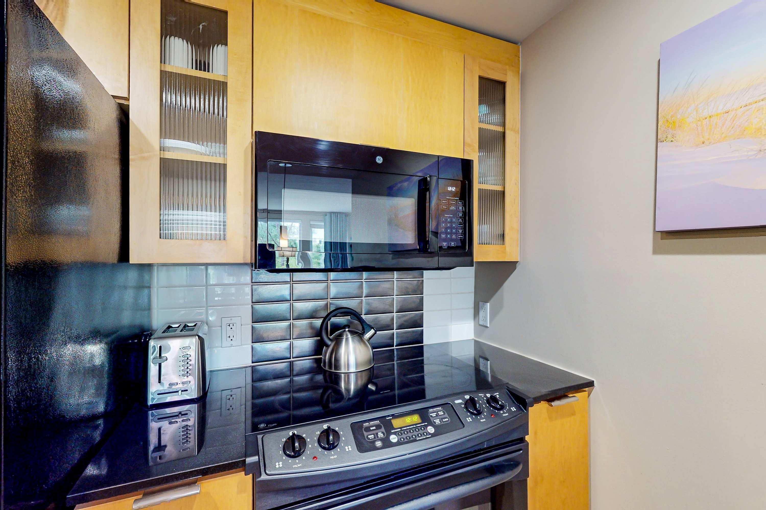 A modern kitchen with a black stove, a kettle, and a microwave.