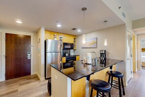 A modern kitchen with a central island, stainless steel appliances, and pendant lighting. - Sunlit condo with washer&dryer, AC, pool, outdoor hot tub, & beach access (Miramar Beach)