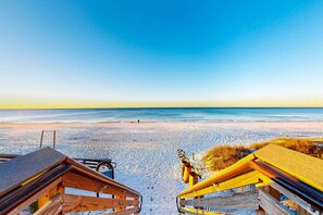 A beach with wooden walkways leading to the water, a clear sky, and a calm sea. - Classic beach home with shared pool access, WiFi, and central air conditioning (Santa Rosa Beach)