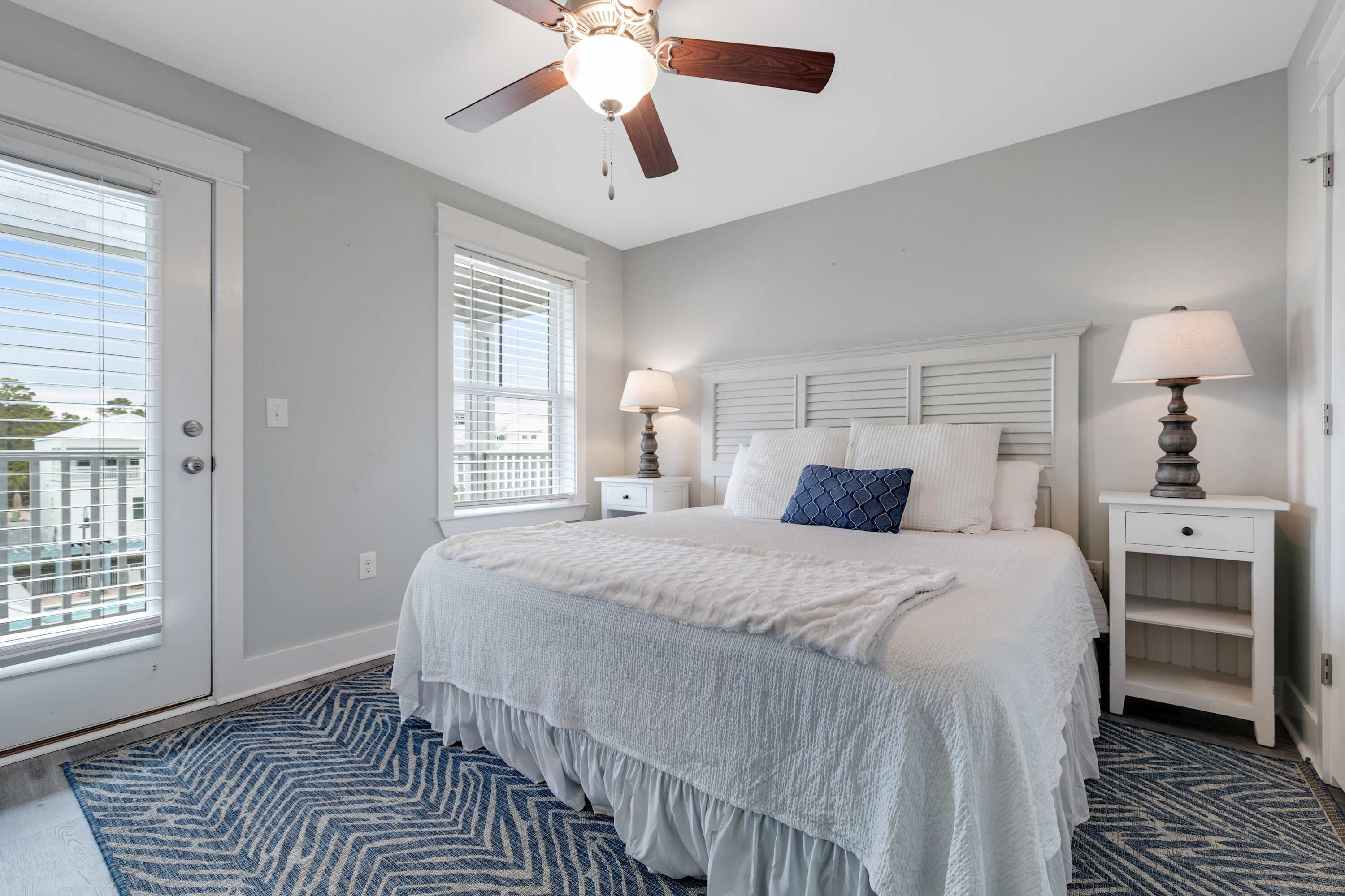 A bedroom with a bed, two bedside tables, a ceiling fan, and a window with blinds. - Classic beach home with shared pool access, WiFi, and central air conditioning (Santa Rosa Beach)