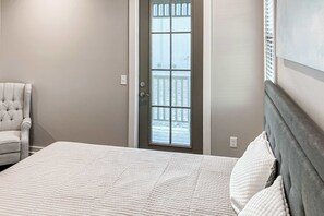 A bedroom with a bed, a chair, and a door with a window. - Charming abode in perfect central location with W&D & central AC - dog-friendly (Port St. Joe)