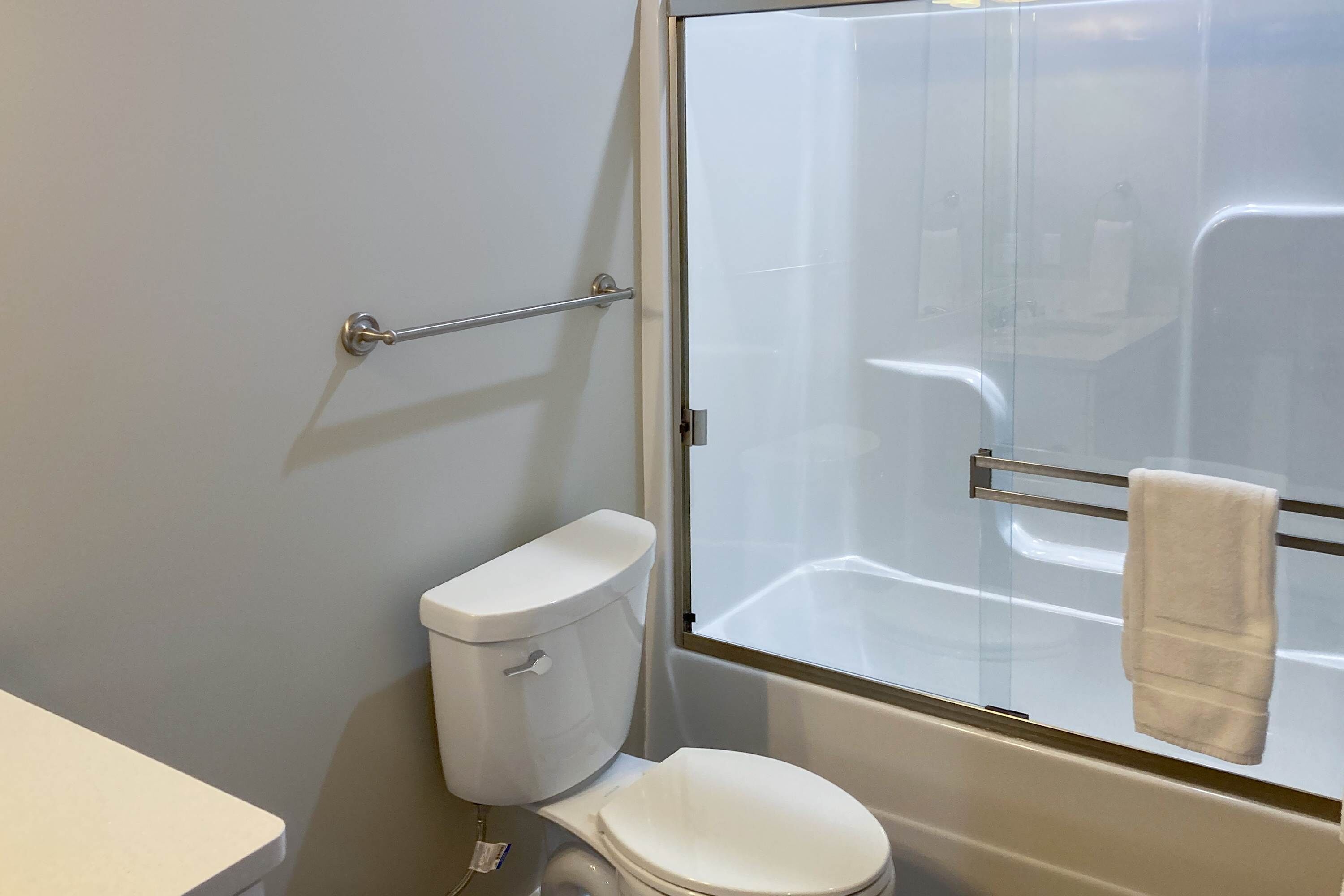 Un baño con inodoro, cabina de ducha de vidrio y toallero.