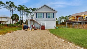A two-story house with a covered porch and a staircase leading to the second floor. - Gorgeous coastal home with plenty of space and easy beach access (St. George Island)