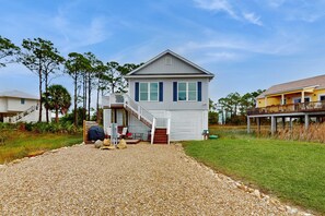 A two-story house with a covered porch and a staircase leading to the second floor. - Gorgeous coastal home with plenty of space and easy beach access (St. George Island)