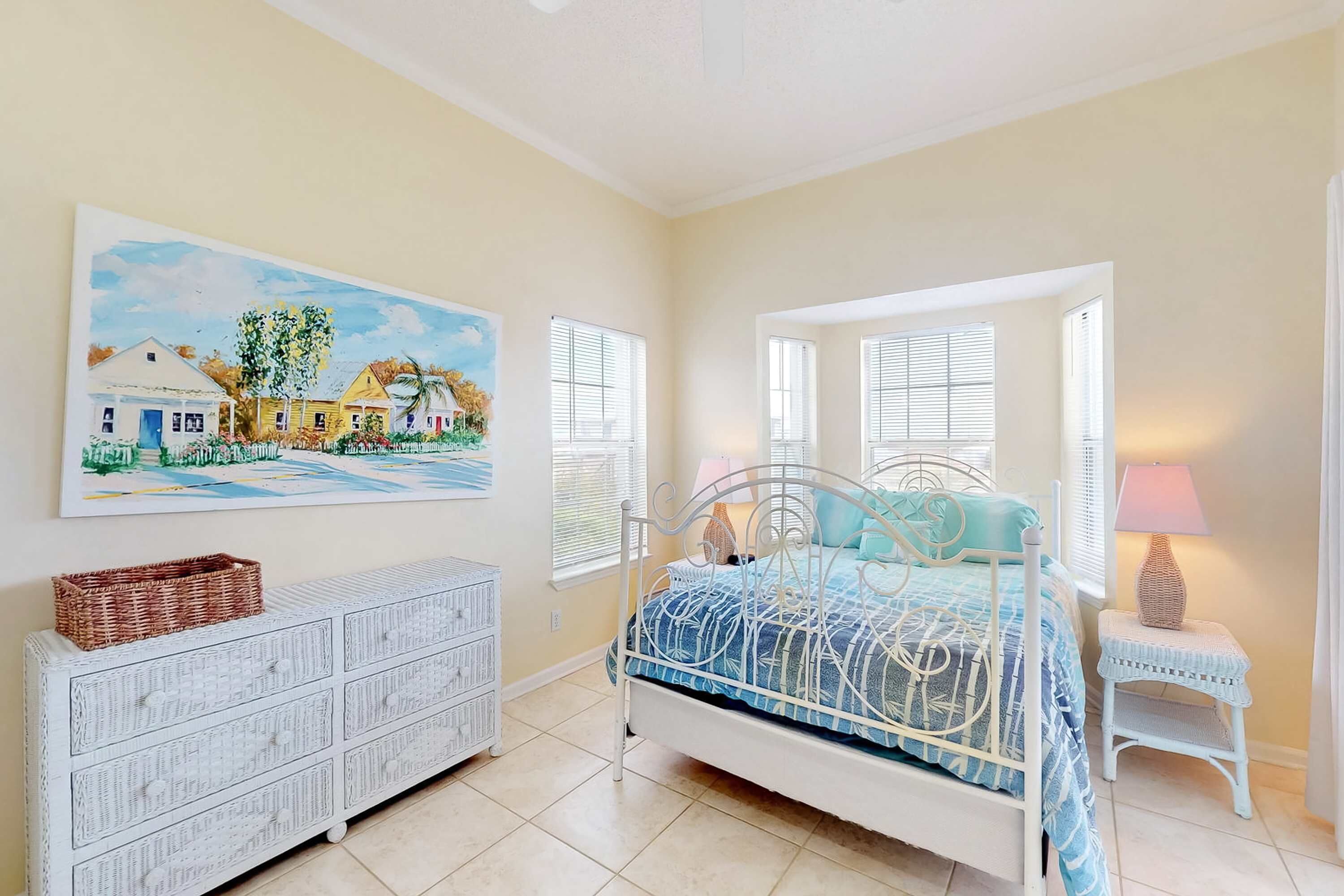 A bedroom with a bed, a dresser, a lamp, and a painting on the wall.