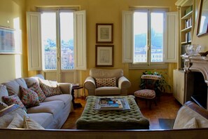 Ein Wohnzimmer mit Sofa, Sessel, Hocker und einem kleinen Tisch mit Pflanze.