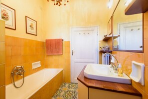 A bathroom with a bathtub, a sink, a mirror, and a door. - Starway to Heaven Apartment (Firenze)